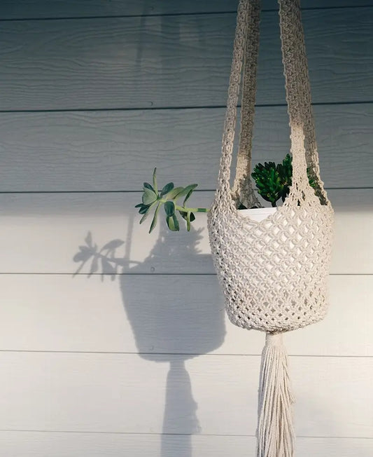 Cream macrame plant hanger with pothos on apartment balcony