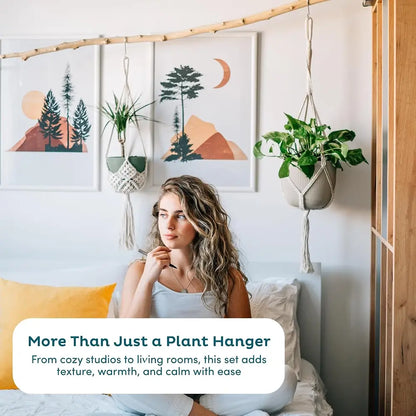 Woman sitting on a bed with plants and wall art in a cozy bedroom setting.