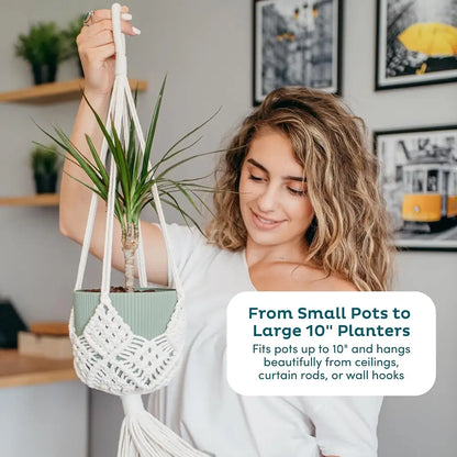 Woman holding a macrame plant hanger with a plant, in a home setting.