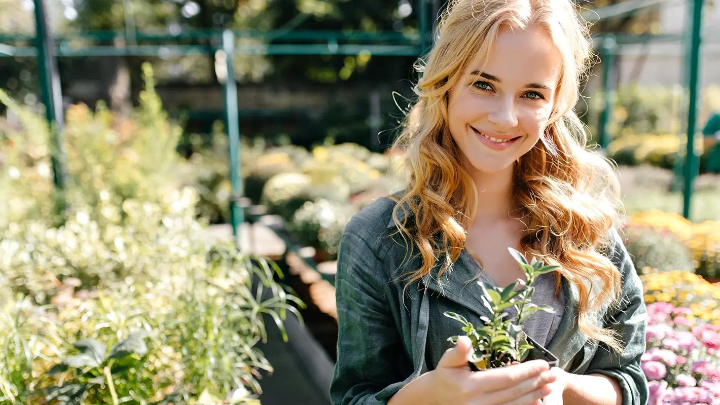 Woman holding a plant in an outdoor garden setting on About My zeno