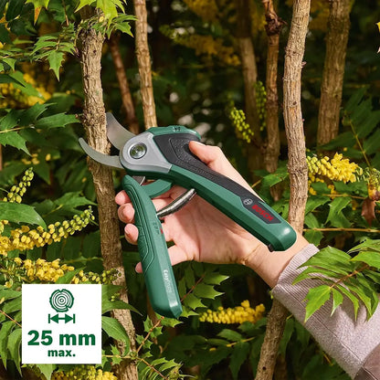 Hand holding green garden shears with a tree and foliage in the background