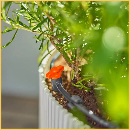 Small garden tool with an orange head and black handle near a potted plant.