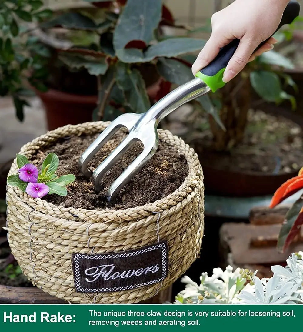Handheld garden rake being used to tend to plants in a woven basket labeled 'Flowers'.