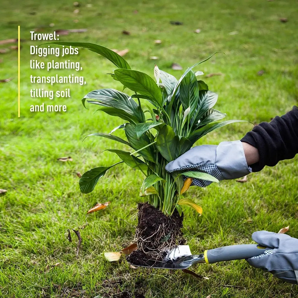 Person planting a plant with gardening gloves and trowel on grass