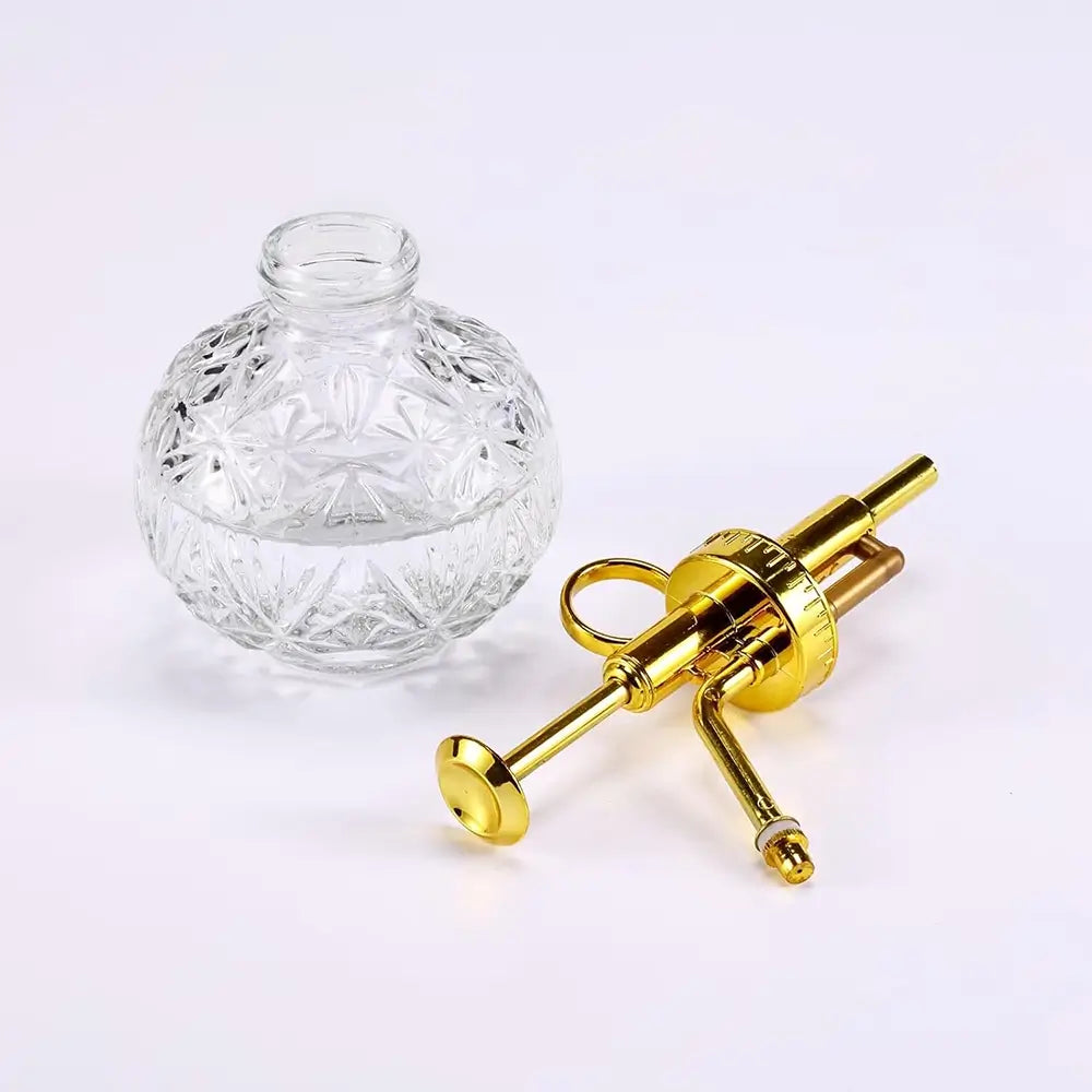 Clear glass bottle with a gold syringe-like device on a white background