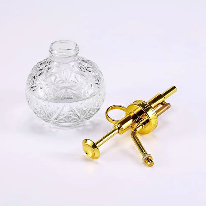 Clear glass bottle with a gold syringe-like device on a white background
