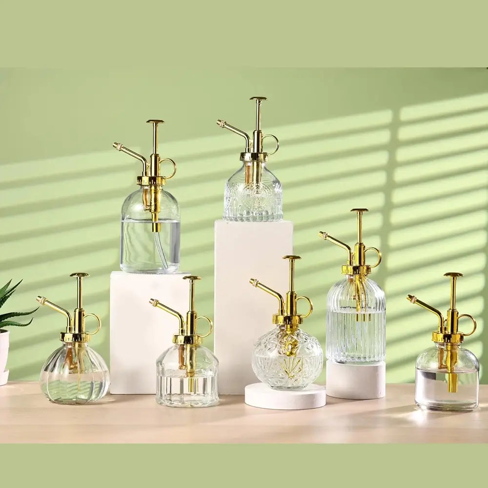 Set of glass and gold spray bottles on a light green background