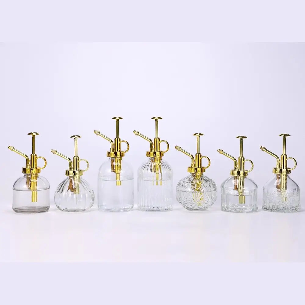 Set of six glass spray bottles with gold nozzles on a white background