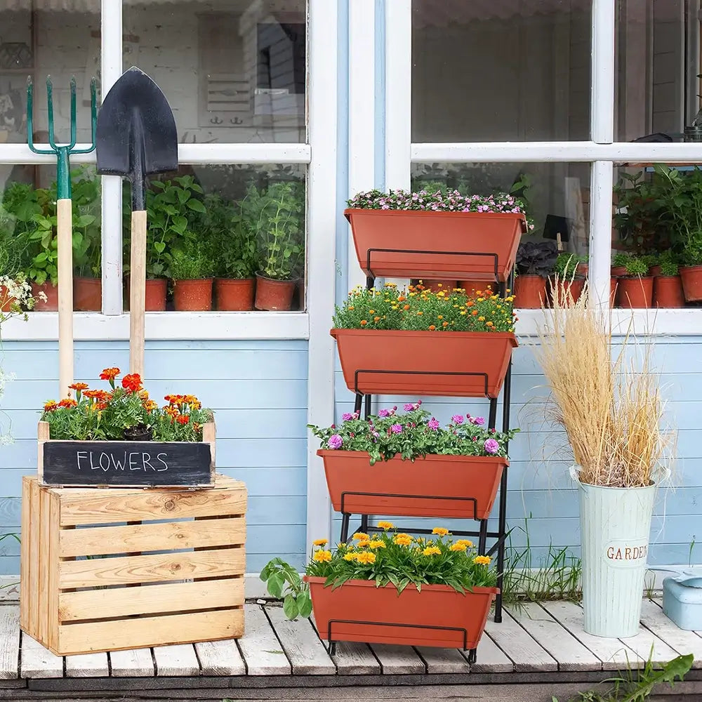 Outdoor garden setup with planters, a wooden crate labeled 'Flowers', and gardening tools on a deck.