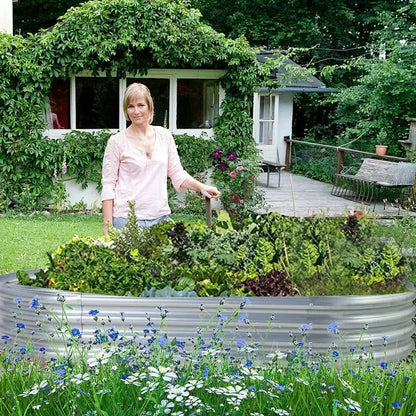 Woman standing in a garden with raised beds and a house in the background
