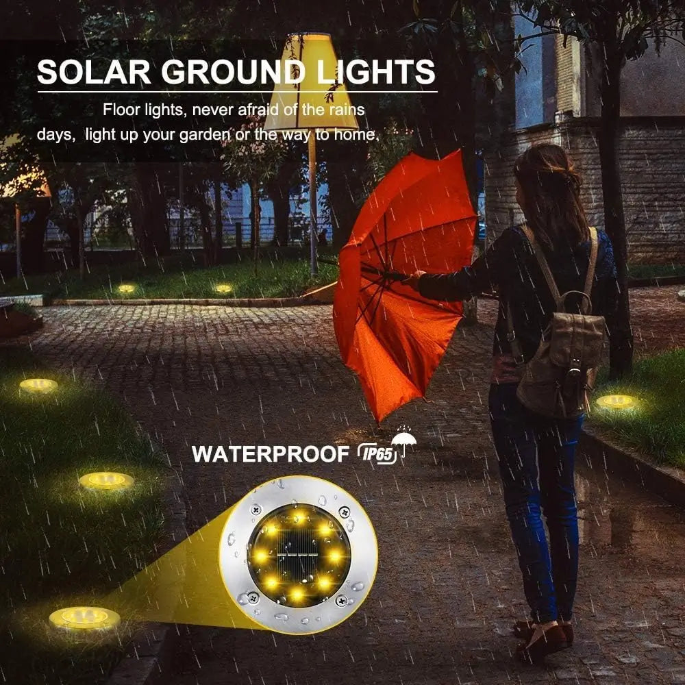 Solar ground lights illuminating a pathway in the rain with a person holding an orange umbrella.