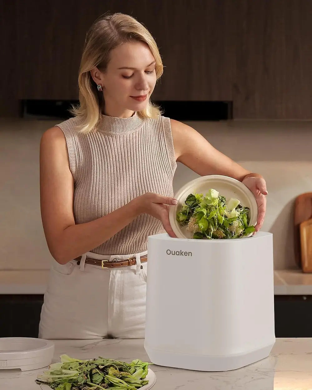 Woman using a white kitchen device labeled 'Ouaken' to prepare food.